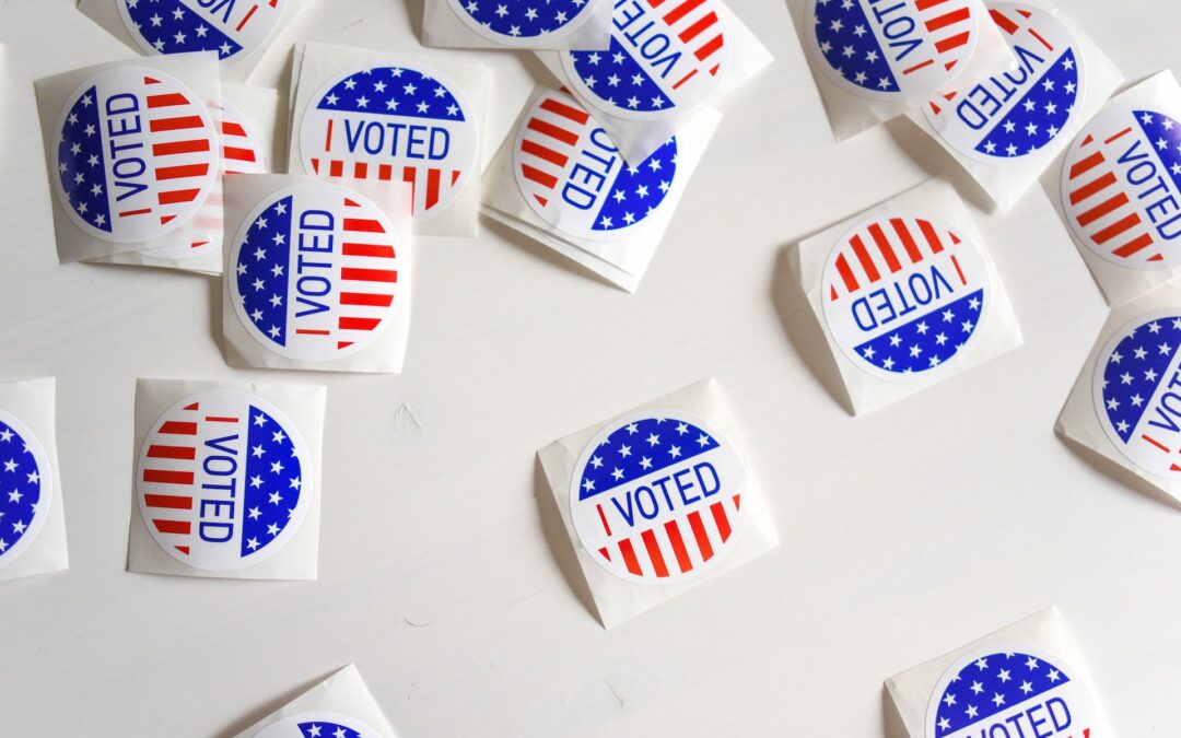 Read, white, and blue "I voted" stickers scattered on a white surface