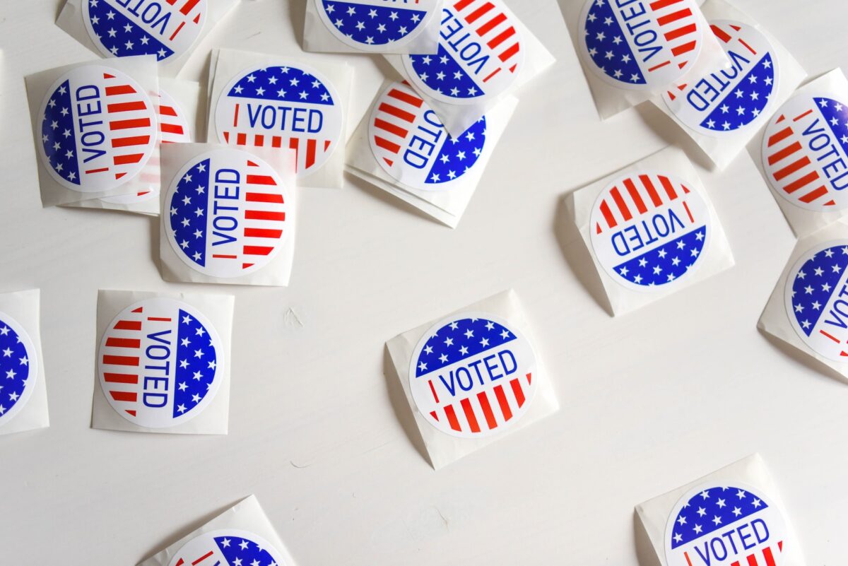 Read, white, and blue "I voted" stickers scattered on a white surface