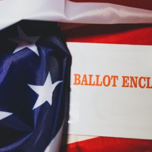American flag with a piece of white paper with the words "Ballot Enclosed" printed on it in bright red