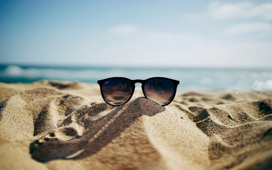 Sunglasses on sand in front of the ocean